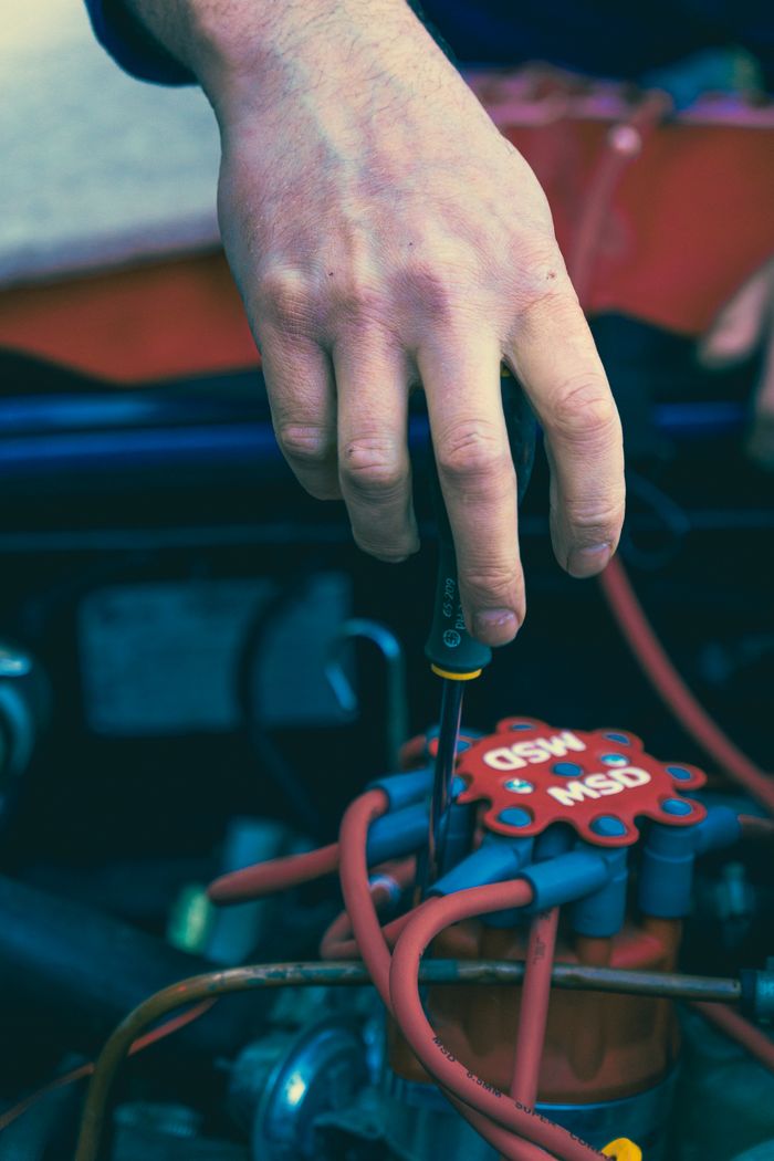 The Art of Drawing Readers In: Your attractive post title goes here Close-up of a man's hand using a screwdriver to repair a car engine, showcasing detailed automotive work.