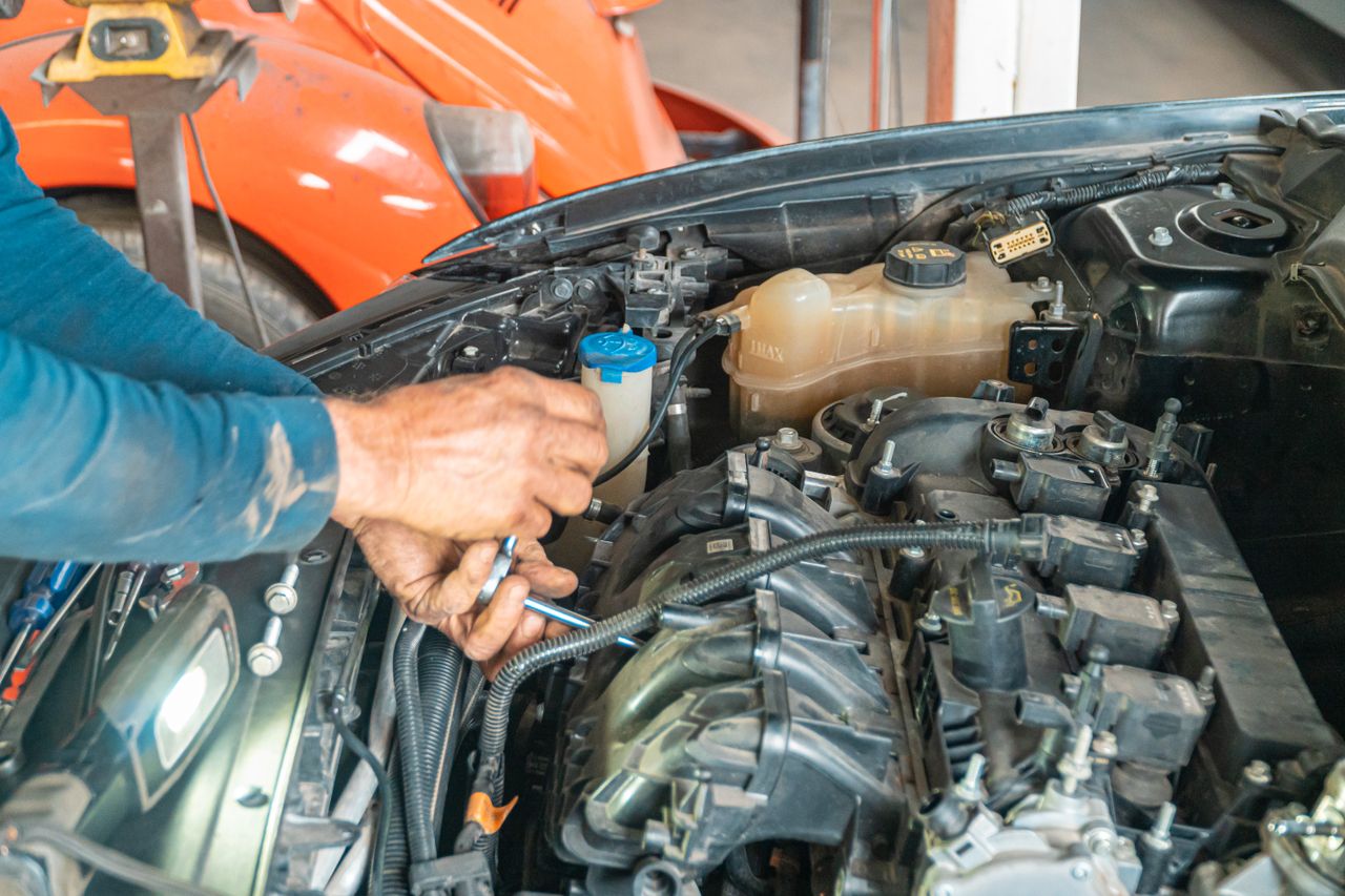 Mechanic's hands repairing a car engine, showing technical precision in an automotive garage.