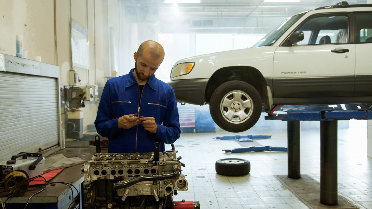 Crafting Captivating Headlines: Your awesome post title goes here A mechanic in blue uniform inspecting an engine in a professional auto repair workshop.